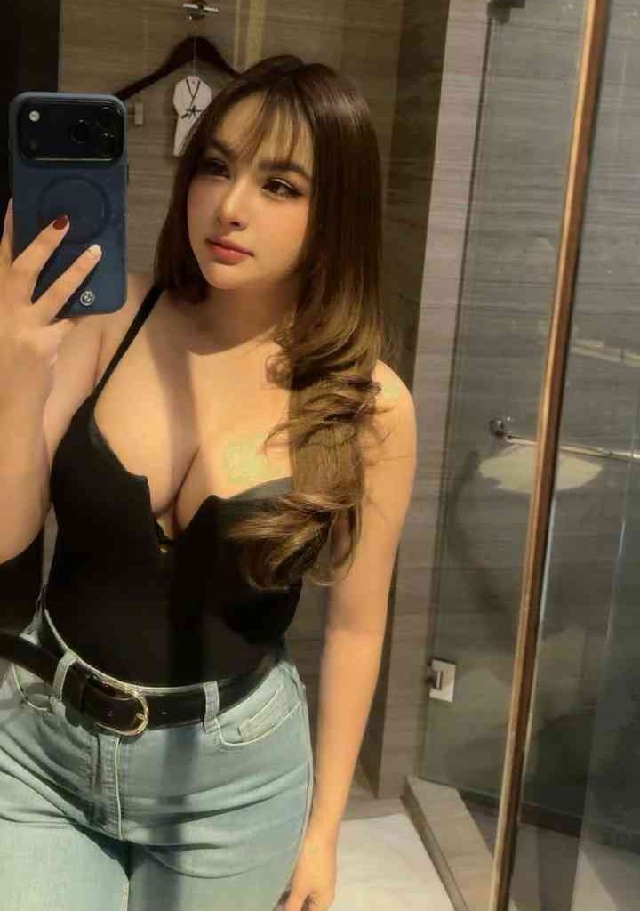 Young Malay woman in black top and jeans taking a mirror selfie in KL.