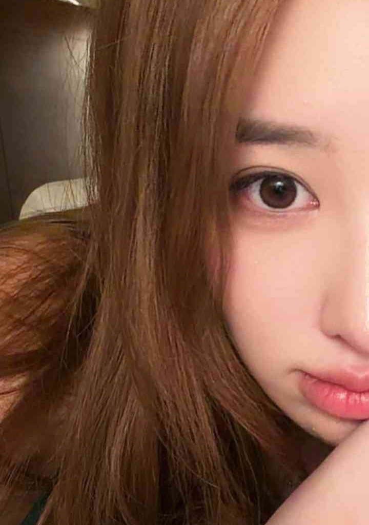 Close-up portrait of Xin Xin, a young Chinese woman with brown hair and expressive eyes.